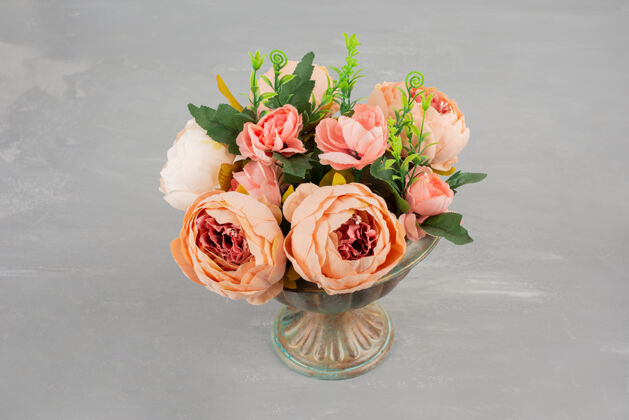 叶子在灰色的桌子上放着一瓶漂亮的粉红玫瑰自然花安排