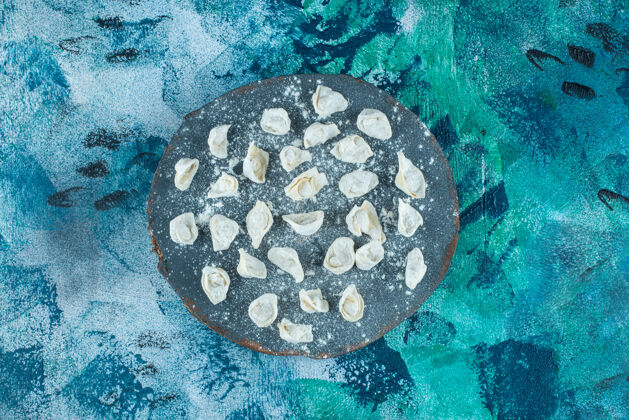 碳水化合物生的土耳其饺子放在板上 蓝色背景美味风味料理