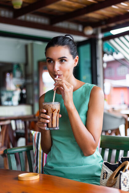 黑发可爱 优雅 平静 快乐的女士 穿着绿色夏装 坐在咖啡馆里喝咖啡 享受早晨年轻放松杯子
