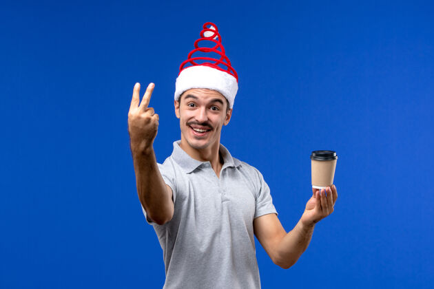 成人正面图年轻男子拿着咖啡杯在蓝色的墙上新年男子节日情绪人杯肖像