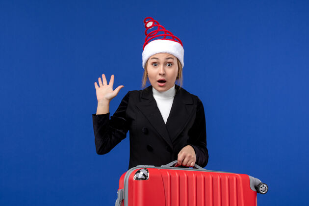 正面正面图年轻女子背着她的大红包在蓝色的墙上度假度假的女人工作圣诞节公司