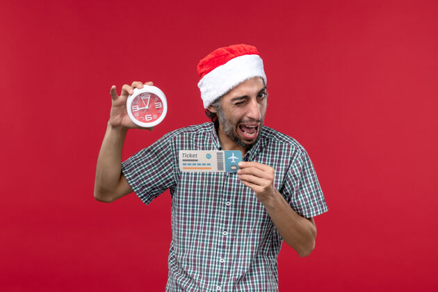圣诞节正面图年轻人拿着红墙上的票和钟红色情感时间男票人人