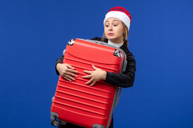 圣诞节前景年轻女士提着大红包在蓝色的墙壁新年假期旅行人成人小姐