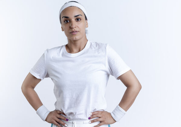 腰年轻自信的白人运动女性戴着头带和腕带把手放在腰上 在空白处与复制空间隔离穿头带腕带