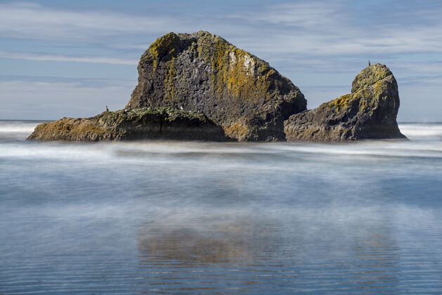 风景在阴天背景下 可以看到一个神秘的岛屿反射到海面上岩石海面阴天
