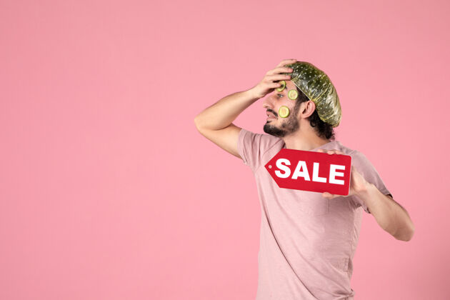 标签正面图：年轻男性 脸上戴着面具 手持粉色背景的销售铭牌视图皮肤销售