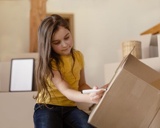 中镜头中等身材的女孩在盒子上写字家庭移动室内