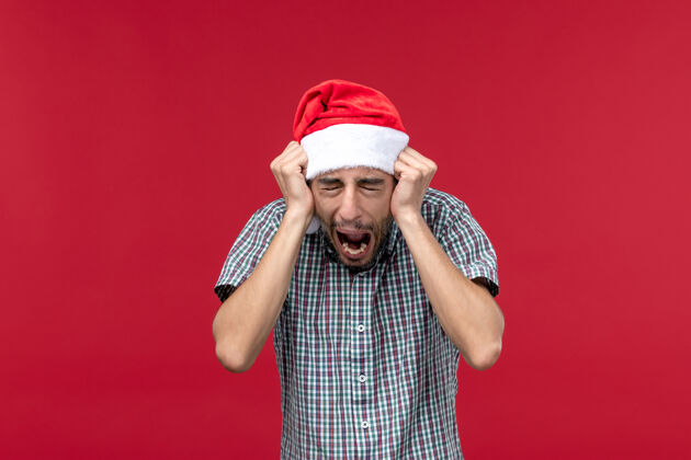 尖叫正面图红色背景上有尖叫表情的年轻男性观点圣诞表情
