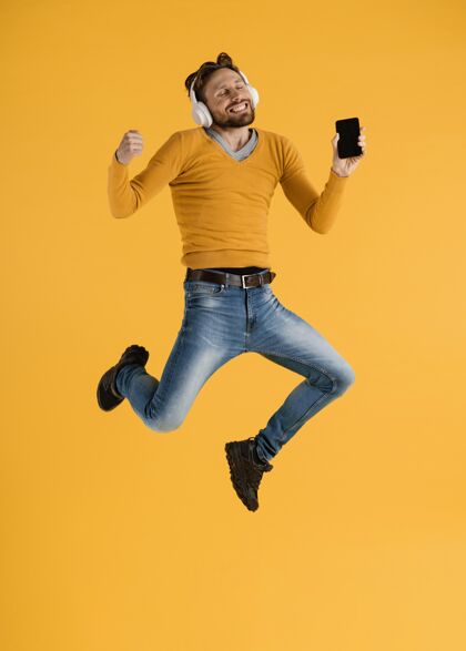 科技带着手机和耳机的年轻人在跳手机跳跃模特