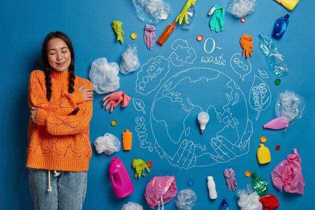女人高兴的年轻女性活动家拥抱自己 感到舒适 在蓝色的墙壁上摆姿势 塑料垃圾遍布全球 与环境污染作斗争垃圾废物环境