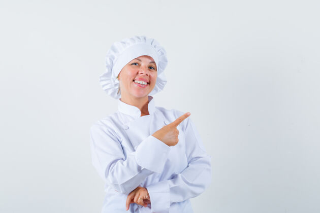 时尚穿着白色制服的女厨师指着右上角 看上去很快乐右人女人