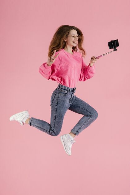 设备肖像快乐的女人用自拍棒跳跃模特姿势年轻