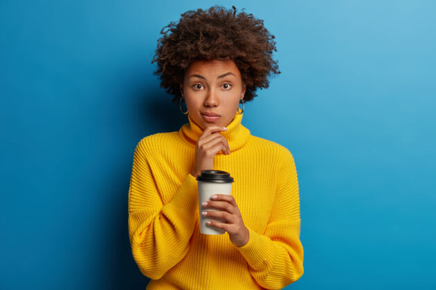人穿着黄色套头衫的美国黑人妇女 喝着外卖咖啡 拿着咖啡馆的杯子人衣服人