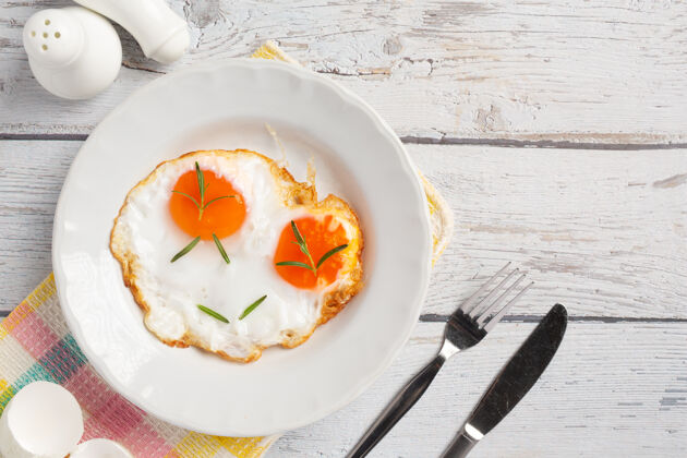 蛋黄在白色的木板上用白色盘子煎鸡蛋胆固醇盘子吃