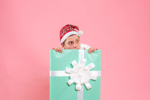 睡衣正面图：穿着白色衬衫的年轻男性 粉色背景上隐藏着礼物正面圣诞节情感