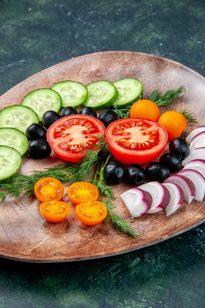 棕色垂直视图新鲜切碎的蔬菜橄榄金橘在棕色盘子上绿黑色混合色背景垂直午餐晚餐