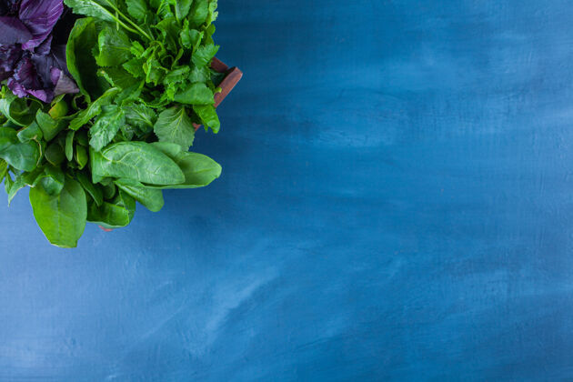 叶子放在蓝色桌子上的健康绿色木盒沙拉有机自然