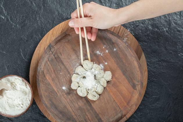 板女人用筷子从盘子里拿饺子手工木头生的