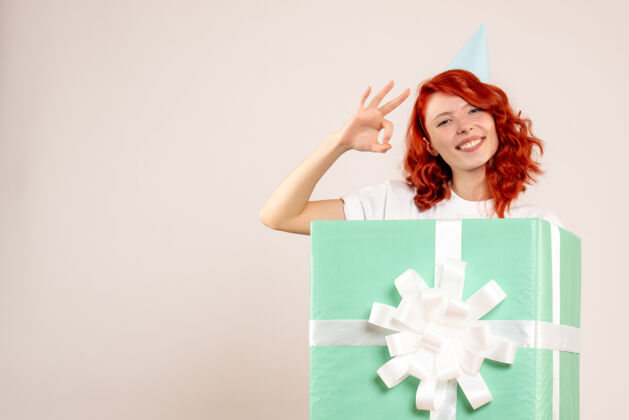 年轻女子正面图：年轻女子在白色背景下微笑丝带礼物圣诞节