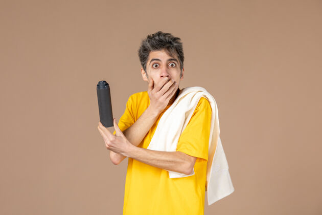 风景正面图：年轻男子拿着泡沫和毛巾准备在粉色背景上刮胡子毛巾泡沫手电筒