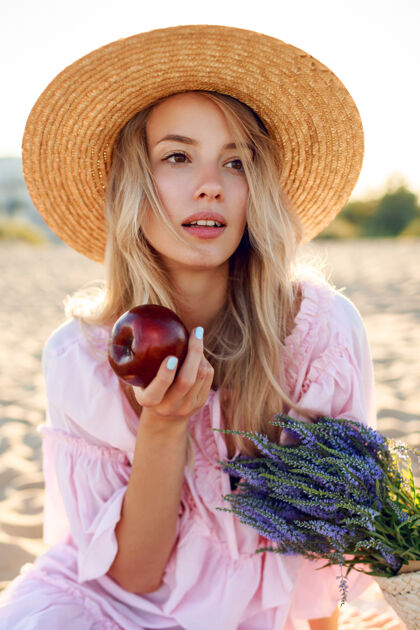 看戴草帽的自然白人女孩在海边享受周末的特写照片与水果合影草包里有一束薰衣草苹果金发自然