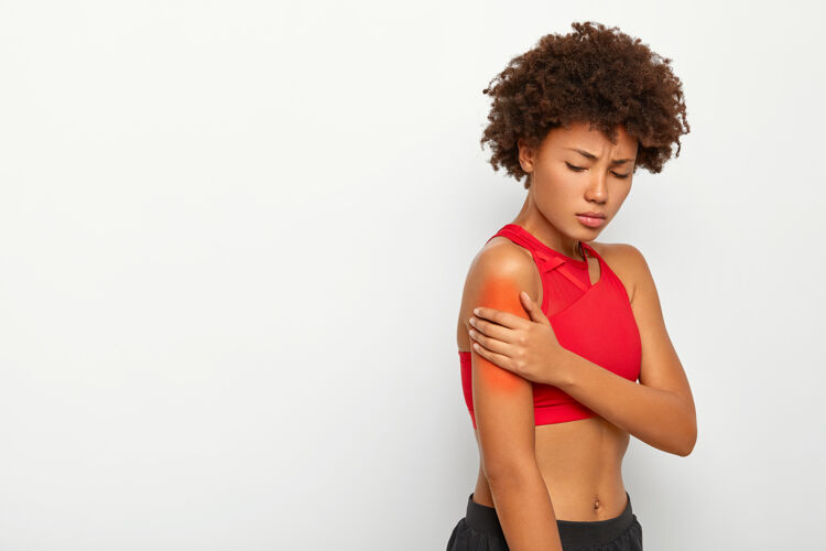 疼痛悲伤的年轻女子手臂肌肉疼痛 在白色背景下侧身站立 在锻炼过程中肩膀受伤抱着僵硬解剖