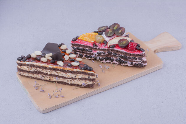 浆果三角形状的巧克力蛋糕片与坚果和水果放在一个木盘上地壳甜食美味