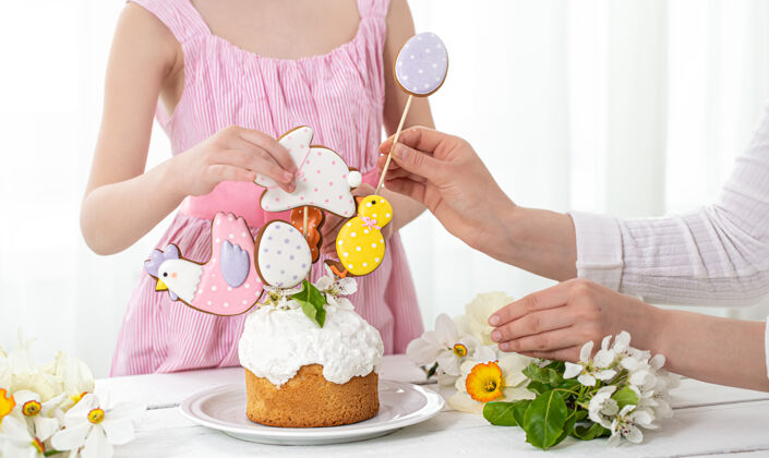 手工制作一个小女孩和妈妈手在装饰节日蛋糕的过程中准备复活节假期的概念自制节日姜饼
