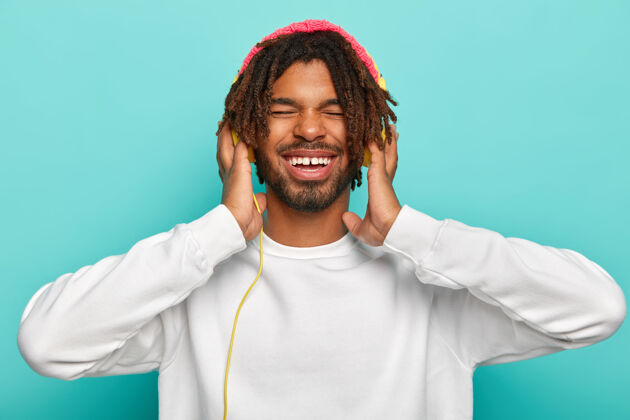 男表情满意的开朗男人 戴着新耳机享受高质量的声音 闭上眼睛 听大声的歌 笑容灿烂笑男人休闲