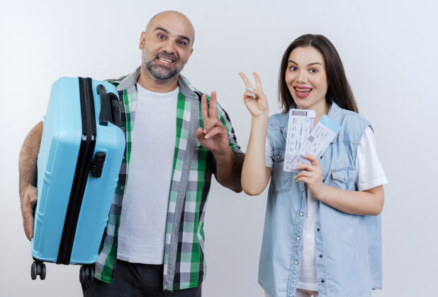 男人快乐的成人旅行者夫妇 男人拿着手提箱 女人拿着旅行票 一边做着和平的手势 一边看着假期假期旅行者