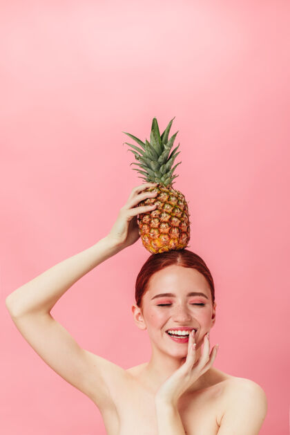 兴奋带着菠萝的裸体女孩闭着眼睛微笑姜汁女郎拿着异国水果的摄影棚镜头微笑女士表情