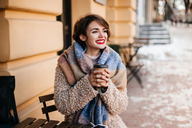微笑热情的短发女人在城里喝咖啡城市现代时尚