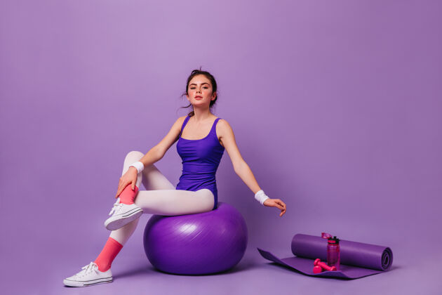 姿势年轻女子在紫色的墙上做健美操粉色袜子女人锻炼