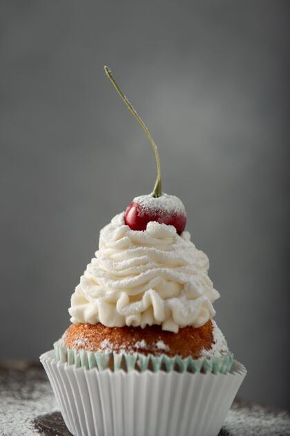 午餐垂直拍摄一个美味的纸杯蛋糕与奶油 糖粉 樱桃上樱桃自制烘焙