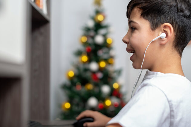 游戏男孩正在用带耳机的电脑圣诞树挂在墙上快乐而兴奋的脸电子学习幼儿园