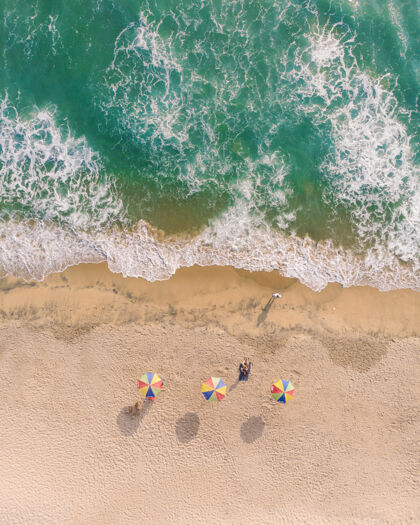 度假瓦卡拉海滩沙滩伞和人们躺在沙滩上的俯视图人波浪自然
