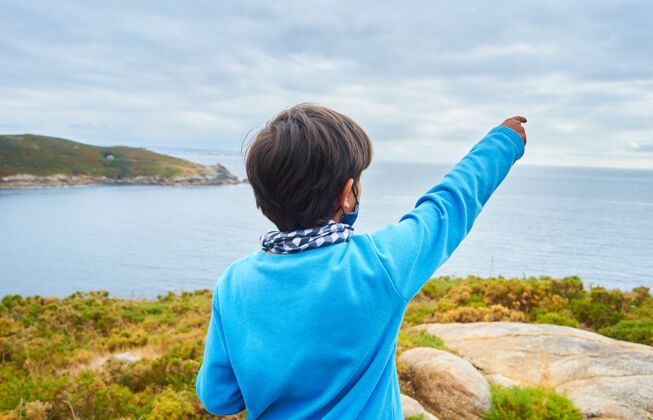 户外一个小男孩站在海景背景上的浅焦镜头年轻人度假