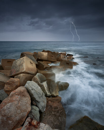 岩石在雷雨和闪电中 海洋中的岩石垂直射击海洋风暴背景
