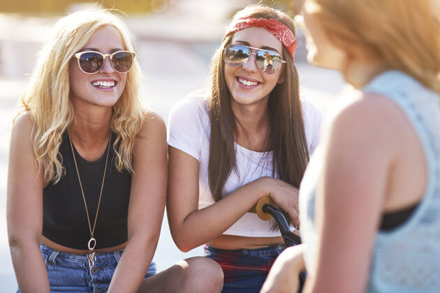 欢呼年轻女子在滑板公园共度时光坐着眼镜太阳镜
