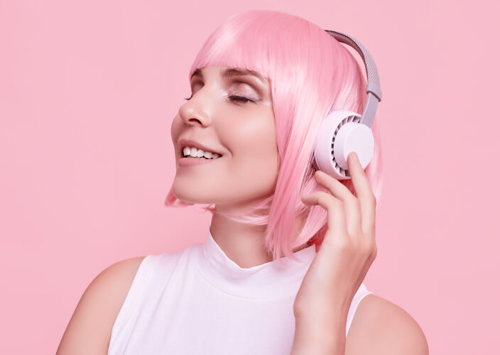 头发粉红头发的美女肖像在耳机里欣赏音乐发型模特脸