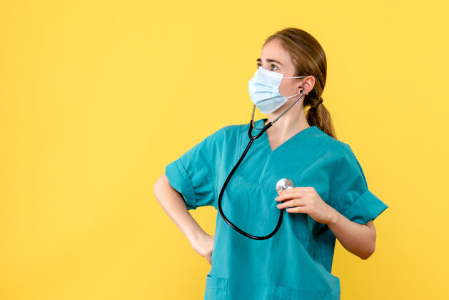 听诊器正面图黄色背景上戴口罩的女医生健康病毒大流行医院设备面罩