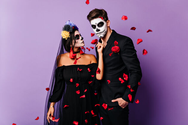 五颜六色可爱的吸血鬼情侣在红色纸屑下合影浪漫的僵尸在万圣节派对上令人毛骨悚然幽灵服装传统