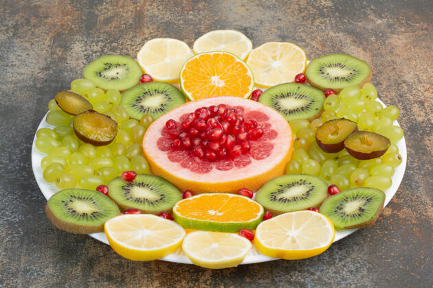 白的新鲜成熟的水果片放在白色盘子里高质量的照片石榴猕猴桃柠檬