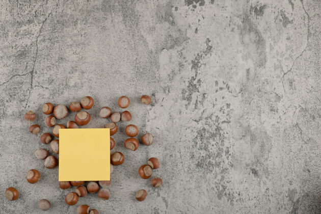 蛋白质健康的澳洲坚果与黄色方形贴纸上的石头背景坚果壳自然内核