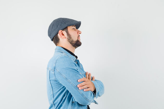 成人复古风格的男人交叉双臂站在夹克衫 帽子立场年轻思考