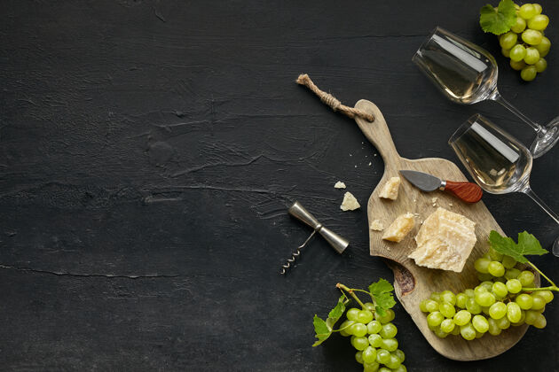 面包两杯白葡萄酒和一个美味的奶酪盘子 在黑石头上的木制厨房盘子上放水果食物波尔多酒厂