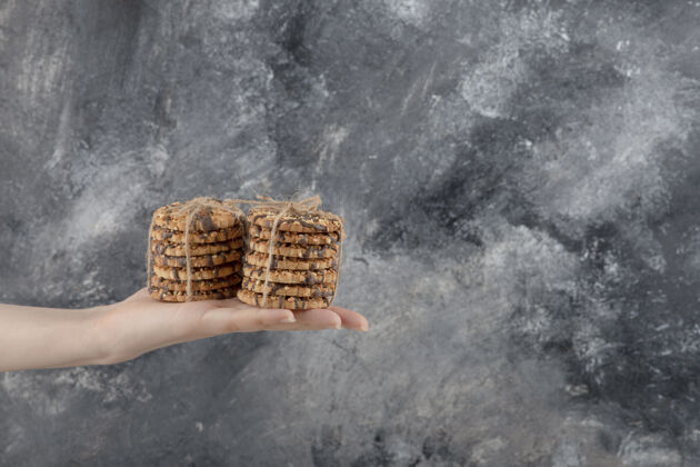 面包房女性手拿一堆燕麦片饼干放在大理石背景上糕点燕麦燕麦