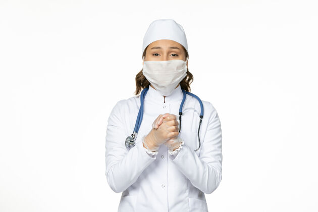 冠状病毒前视女医生穿着白色医疗服戴口罩因白色办公桌上冠状病毒大流行病毒隔离到期医生面罩