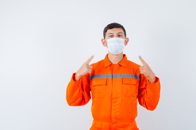 焊接一个穿着制服的工业工人指着他的医用面罩 仔细地看着前方指向控制护理