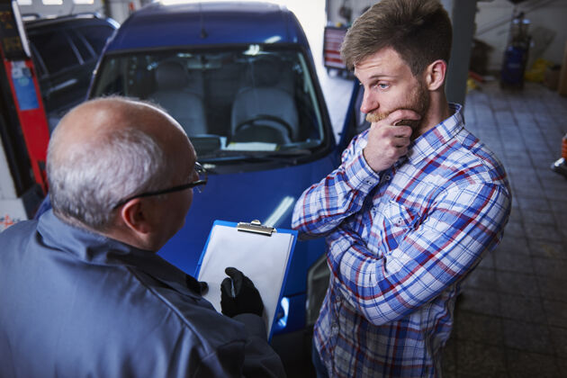 客户客户在车间和一个机械师交谈防护服汽车修理厂谈话